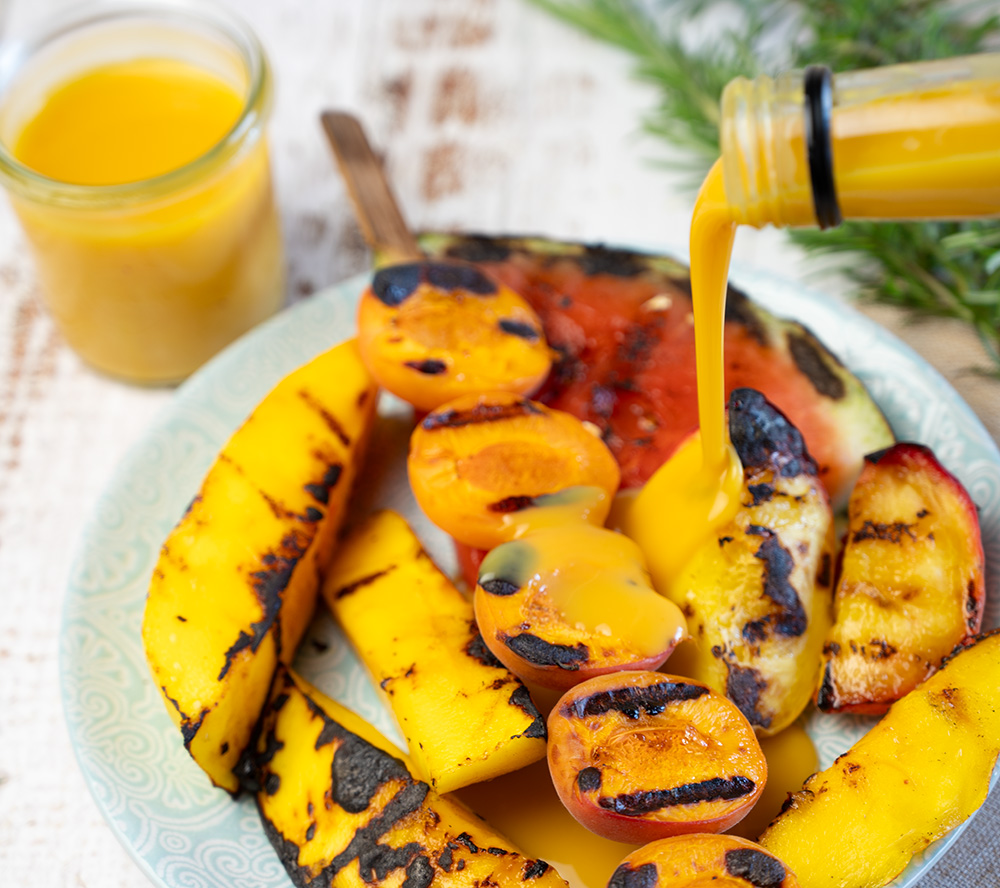 Eierlikoer fliesst ueber gegrilltes Obst Eierlikoer fliesst ueber gegrilltes Obst